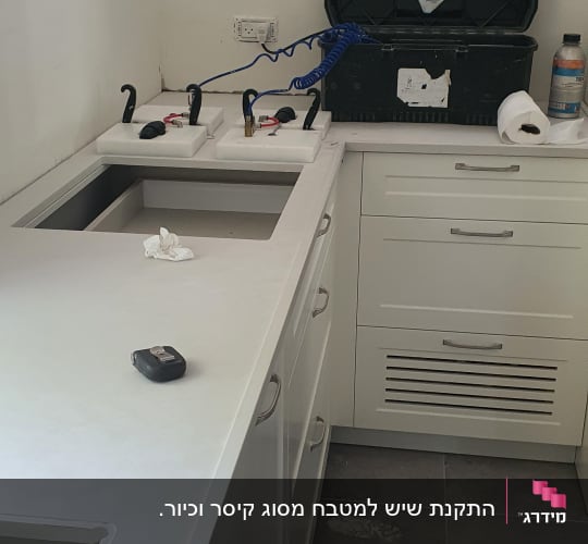התקנת משטח שיש לבן במטבח עם פתחים מותאמים לכיור ולכיריים